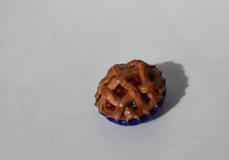 Small decorative cherry pie with a lattice design on a white background