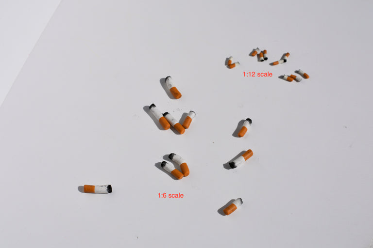 Small model cigarettes on a white background with scale indicators.