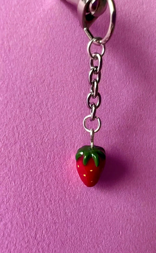Strawberry-shaped keychain charm on a pink background