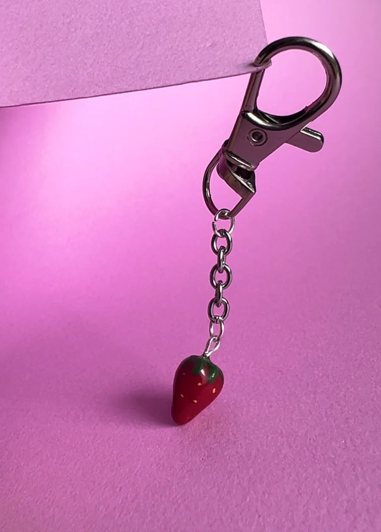 Strawberry-shaped keychain on a pink background