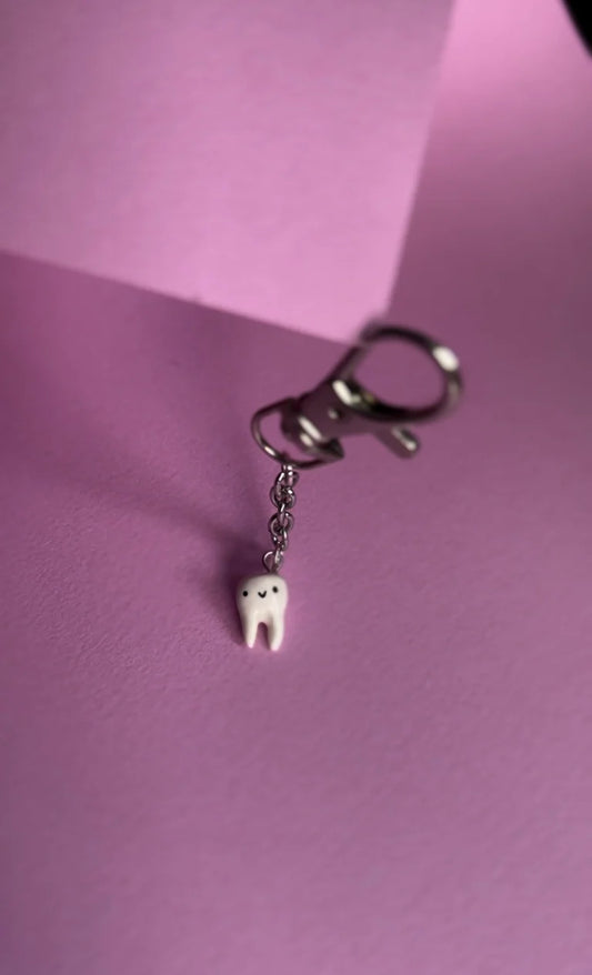 Keychain with a tooth charm on a pink background