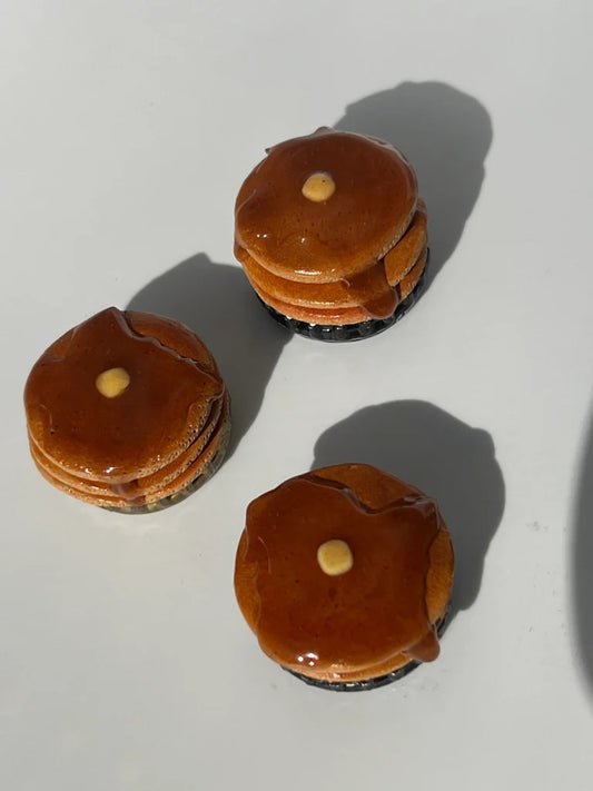 Three small brown stacked pancakes with a white background