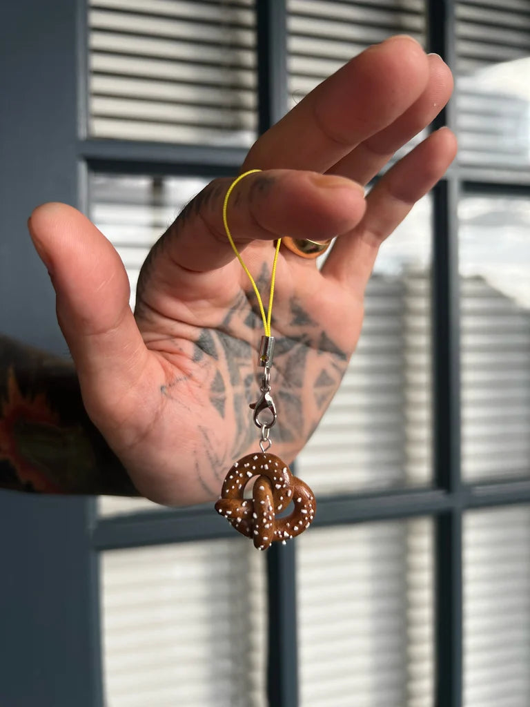Hand holding a decorative keychain with a blurred window background