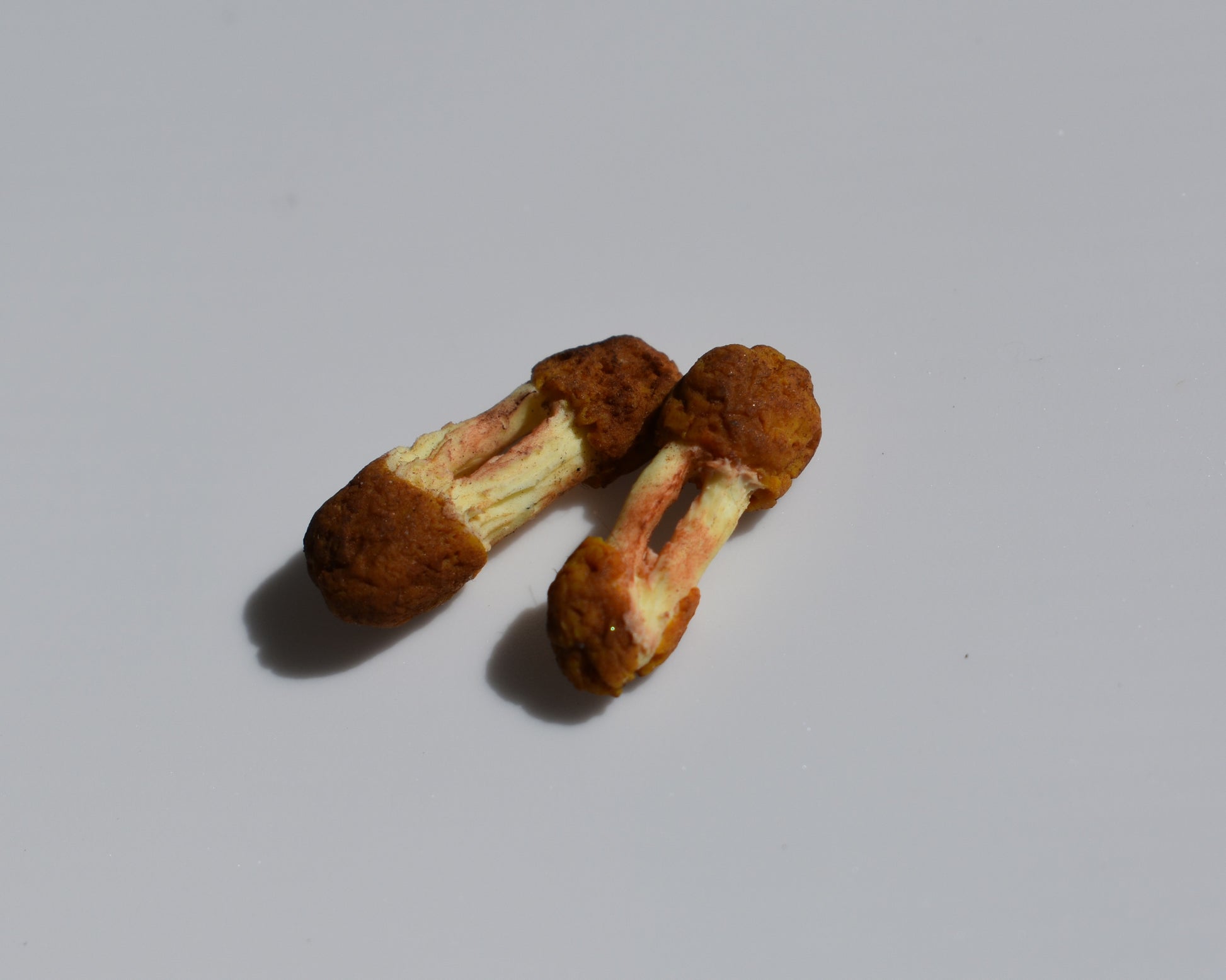 Two small fried, eaten chicken wings, both are flats. They are on a white background.