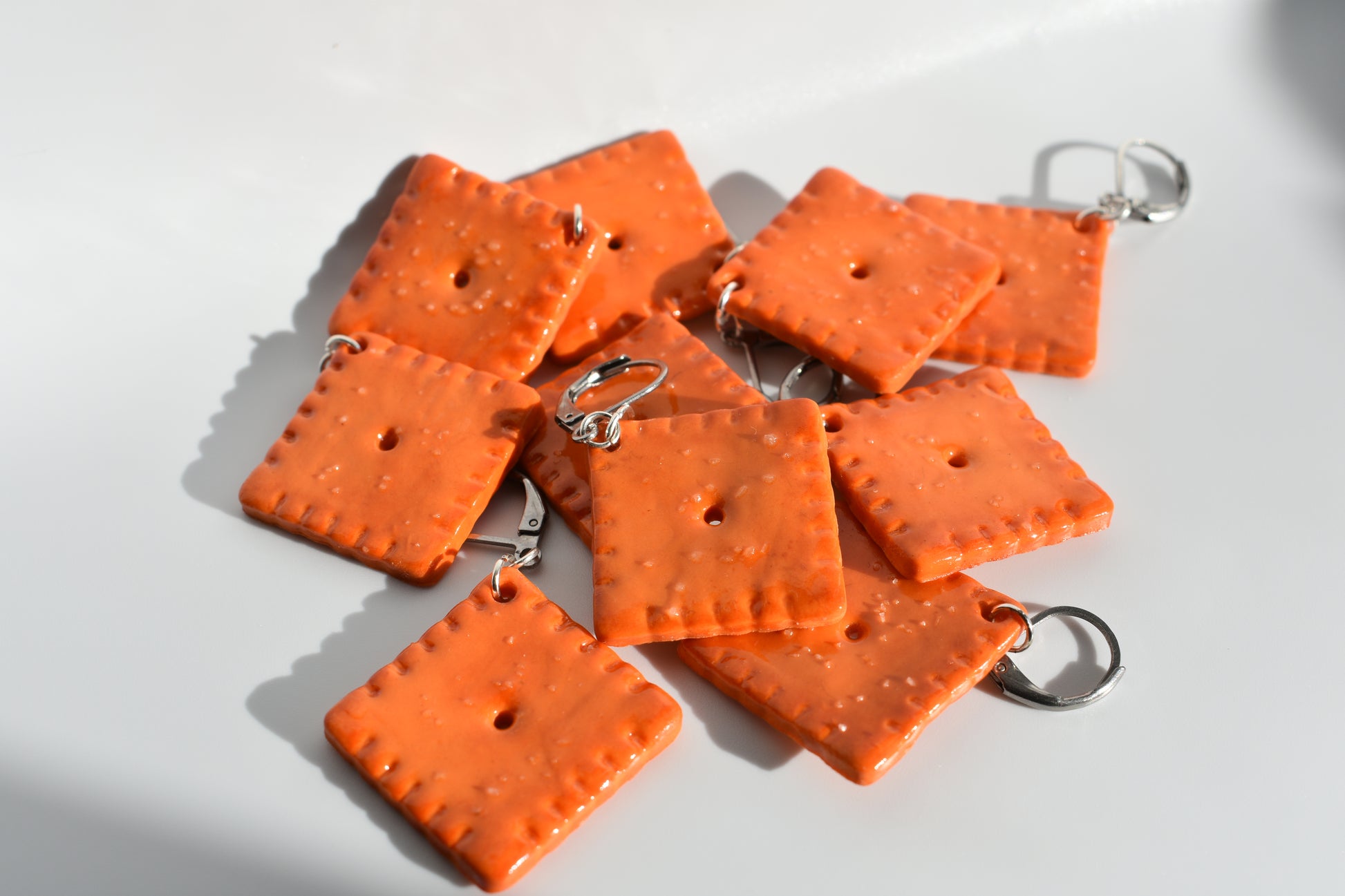 Orange square-shaped keychains with metal loops on a white background