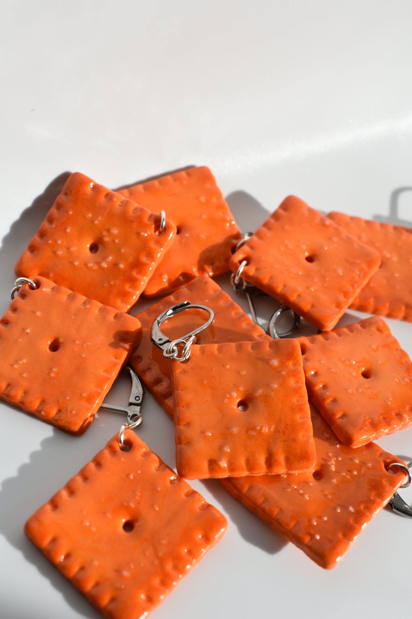 Orange square-shaped cheddar cracker looking crochet markers on a white background