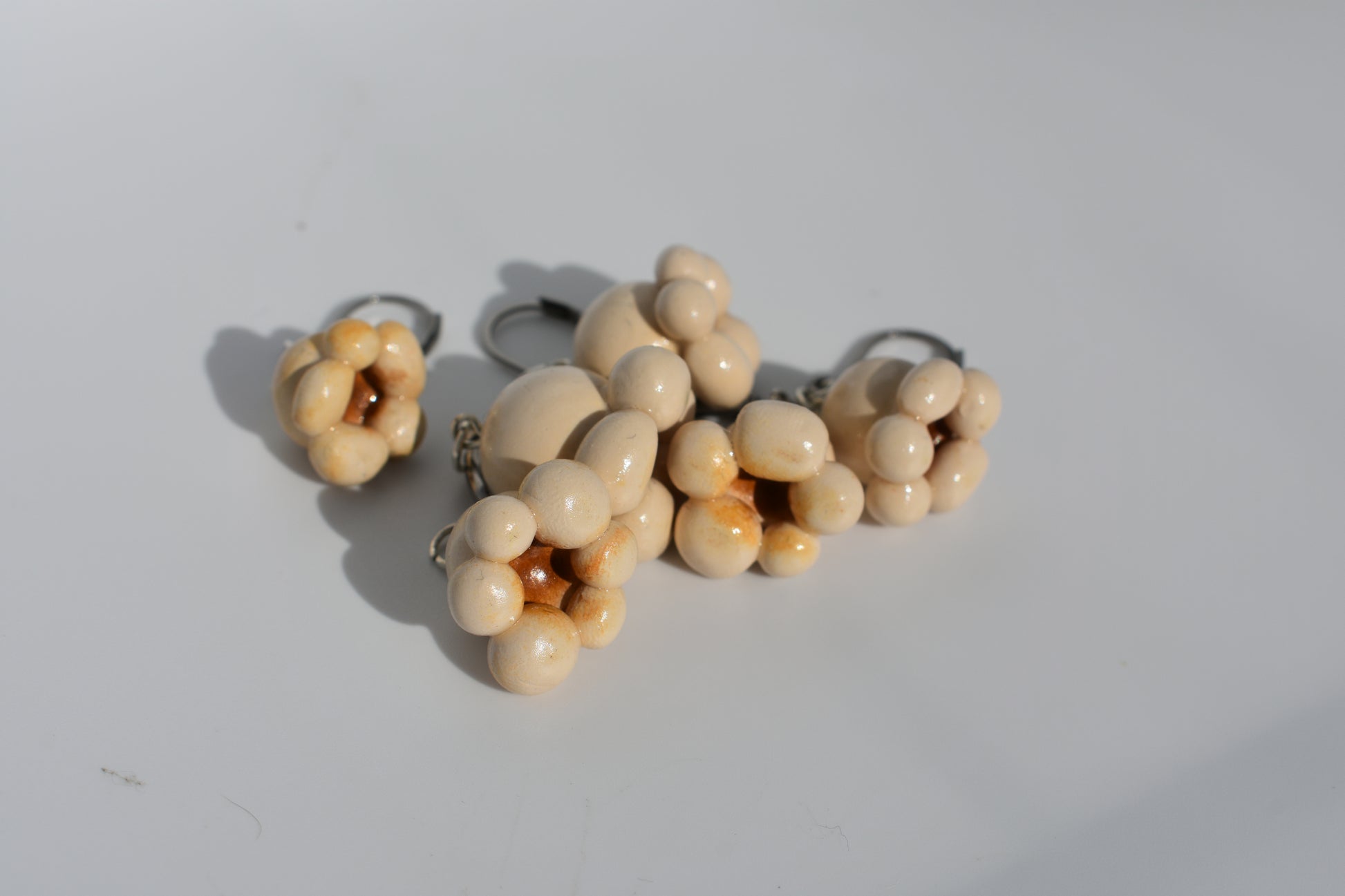 a group of 6 beige polymer clay popcorn stitch markers in a pile on a plain white background.