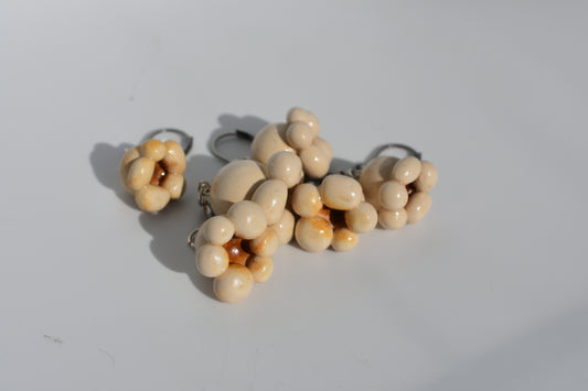 a group of 6 beige polymer clay popcorn stitch markers in a pile on a plain white background.