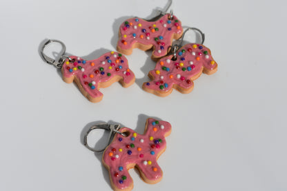 Animal cookie-shaped keychains with pink frosting and sprinkles on a white background