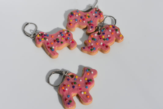 Animal cookie-shaped keychains with pink frosting and sprinkles on a white background