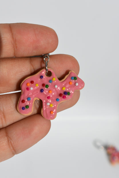 Pink cookie-shaped keychain with sprinkles held in a hand against a white background