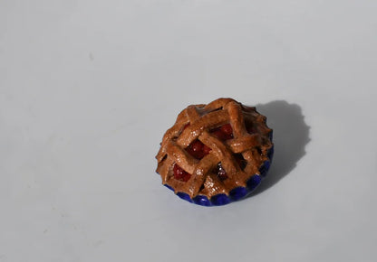 Small decorative cherry pie with a lattice design on a white background
