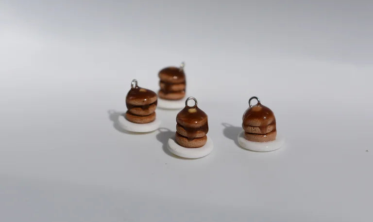 Four small brown and white ceramic charms on a white background