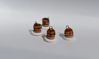 Four small brown and white ceramic charms on a white background