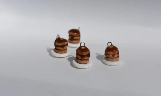 Four small brown and white ceramic charms on a white background