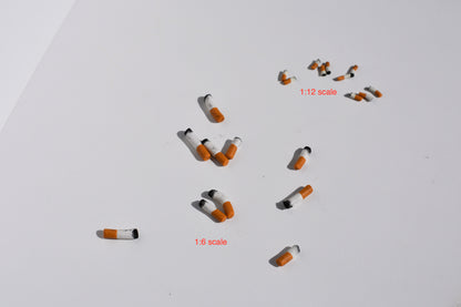 Small model cigarettes on a white background with scale indicators.