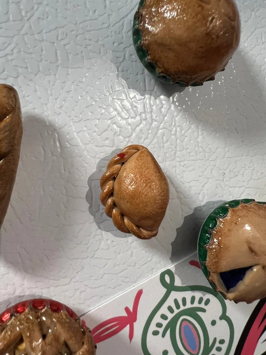 Decorative miniature empanadas on a textured white refrigerator.