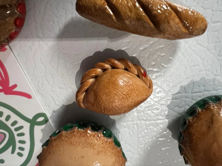 Close-up of a braided bread roll on a textured white surface with a colorful box in the background.