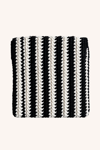 A square black and beige striped knit pouch with a textured, ribbed pattern, shown flat on a beige background.