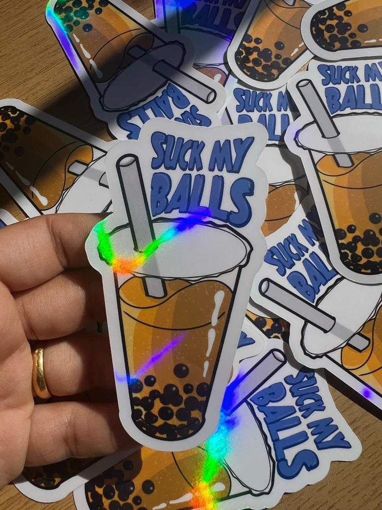 Sticker with a drink design and text 'Suck My Balls' held by a hand.