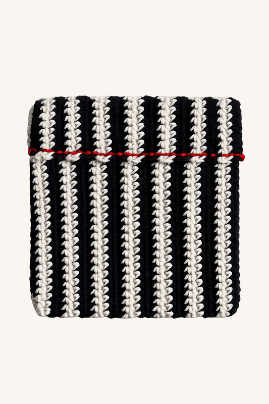 A square knit pouch featuring vertical black and off-white stripes with a thin red horizontal stripe across the middle, shown on a plain beige background.
