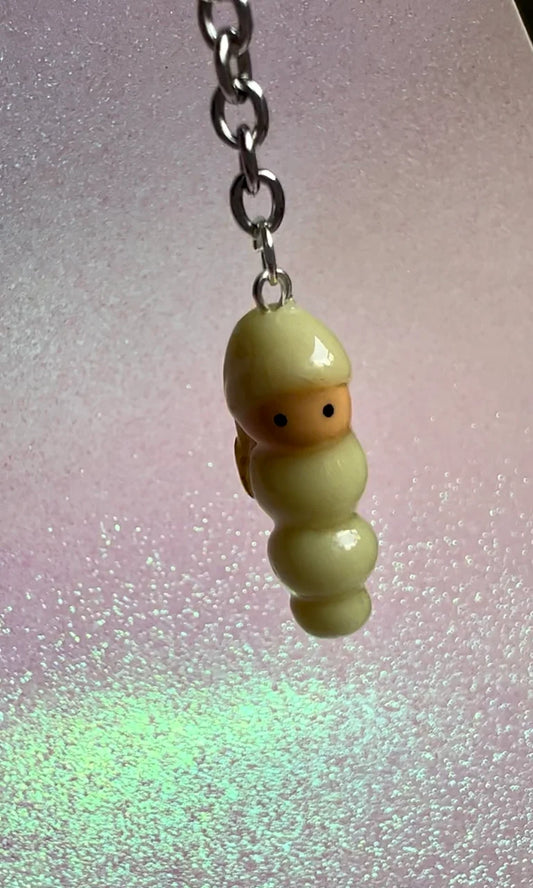 Small glow in the dark worm character from the 80's and 90's on a chain against a glittery background