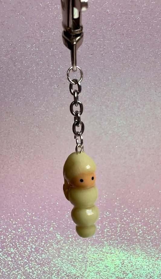 Small glow in the dark worm character from the 80's and 90's on a chain against a glittery background