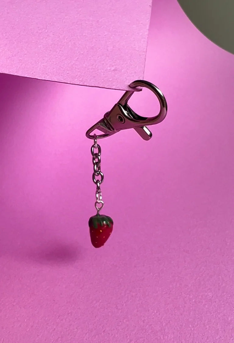 Keychain with strawberry charm on a pink background