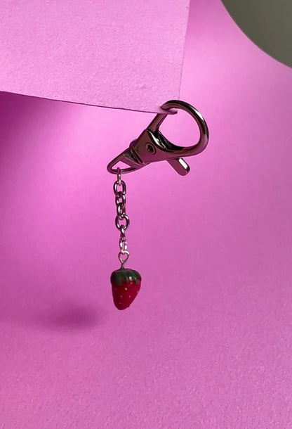 Keychain with strawberry charm on a pink background