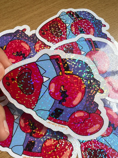 Colorful glittery sticker with cartoon character held by a hand on a wooden surface