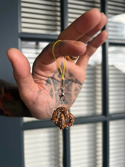 Hand holding a decorative keychain with a blurred window background