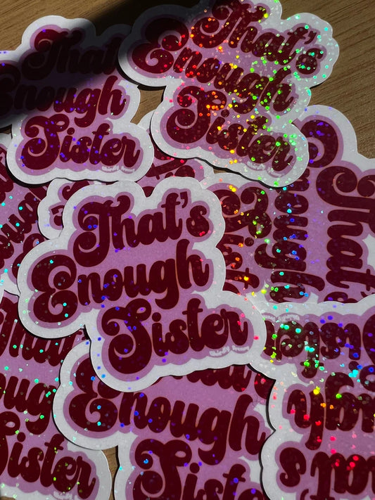 Stack of 'That's Enough Sister' stickers with glittery text on a wooden surface