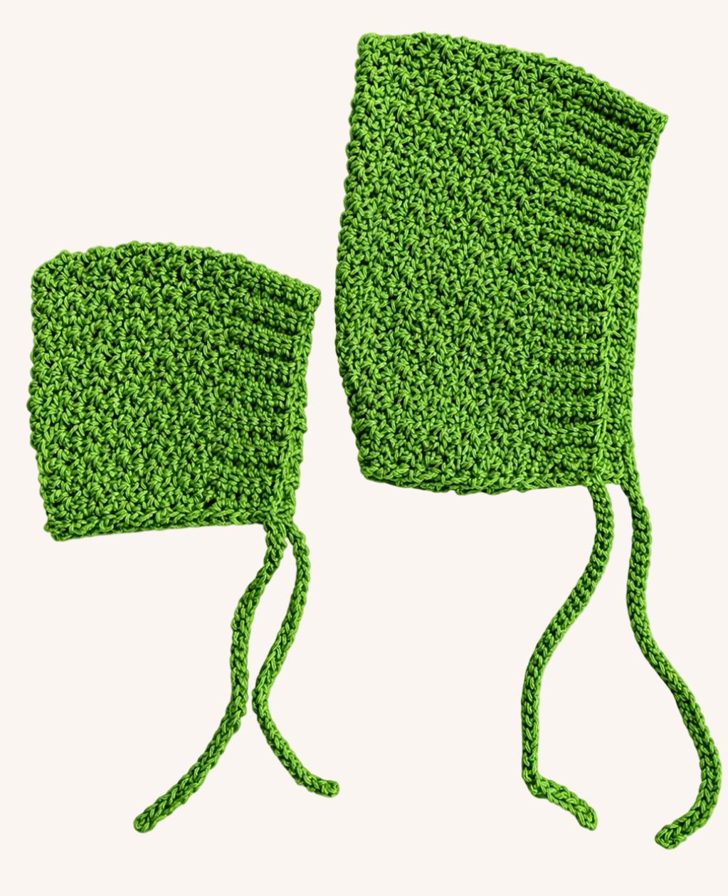 two kelly green, crochet baby bonnets laying side by side. One is in a small, newborn size while the other is in a 6-9 month old size.